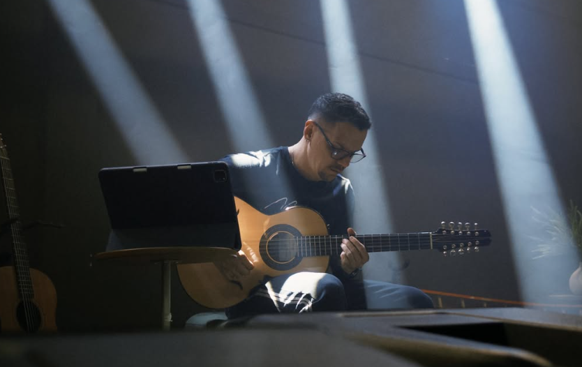 Zaidan tocando violão sob fachos de luz no palco